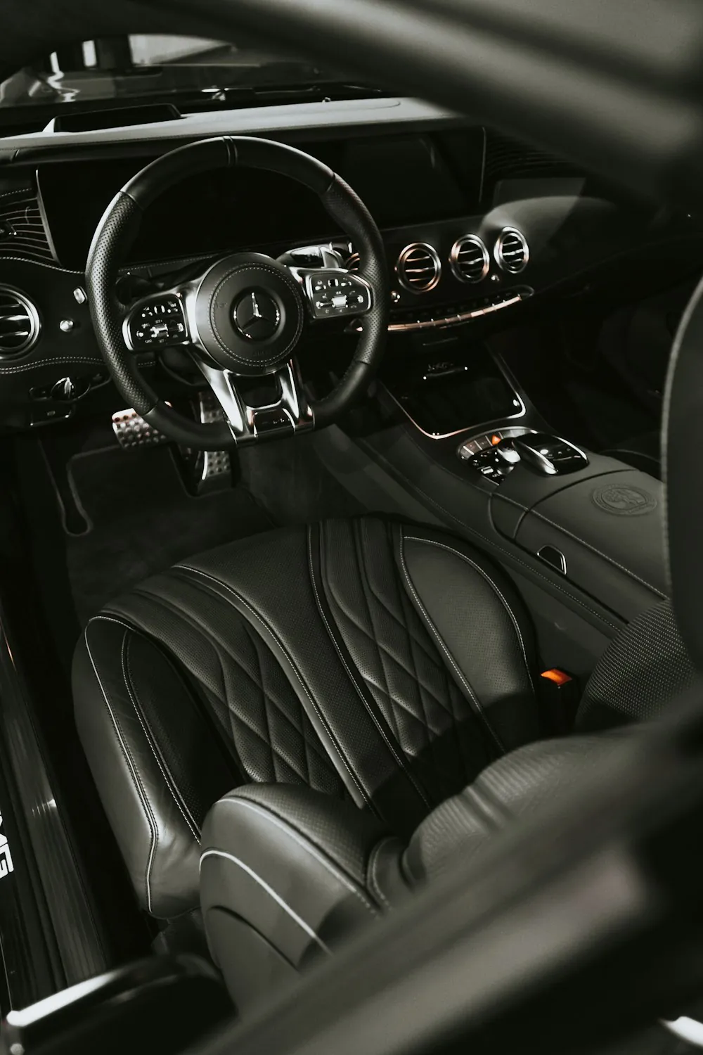 A black quilted leather car interior with a flat-bottom steering wheel